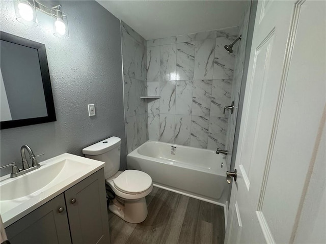 bathroom with wood finished floors, vanity, toilet,  shower combination, and a textured wall