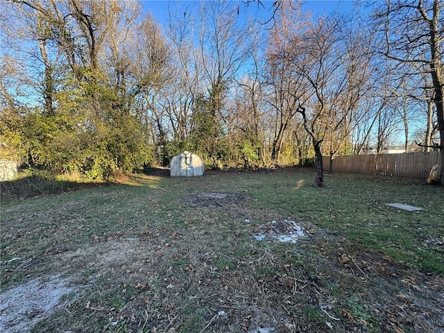 view of yard with a storage shed, fence, and an outbuilding