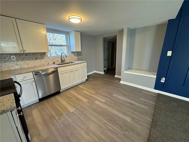 kitchen with stainless steel dishwasher, a sink, range, backsplash, and baseboards