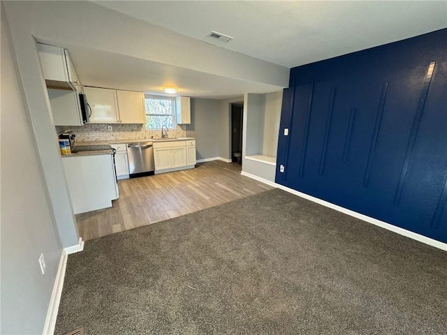 kitchen with white cabinets, baseboards, light carpet, and appliances with stainless steel finishes