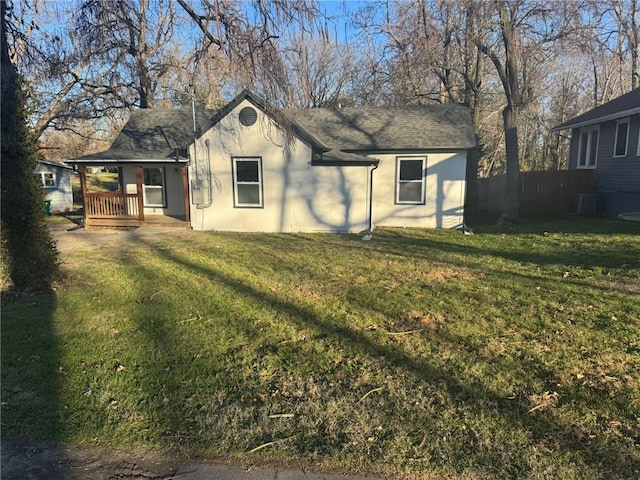 rear view of house featuring covered porch, a yard, roof with shingles, and central air condition unit
