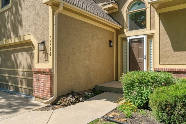 5714 Alden Ct, Shawnee, KS 66216 - doorway to property featuring a garage, stucco siding, and roof with shingles