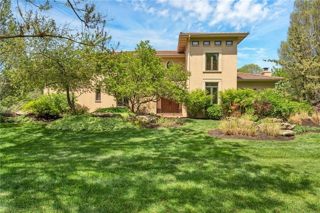 back of house featuring stucco siding and a lawn