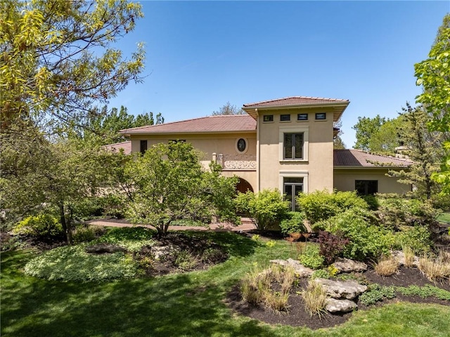rear view of property featuring stucco siding and a yard
