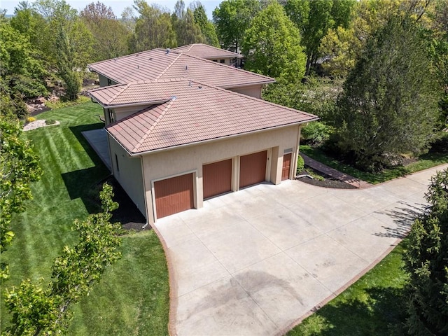 view of side of home featuring driveway, a tile roof, a yard, and stucco siding