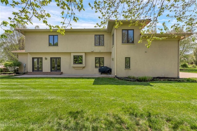 rear view of house featuring stucco siding, french doors, a patio area, and a lawn