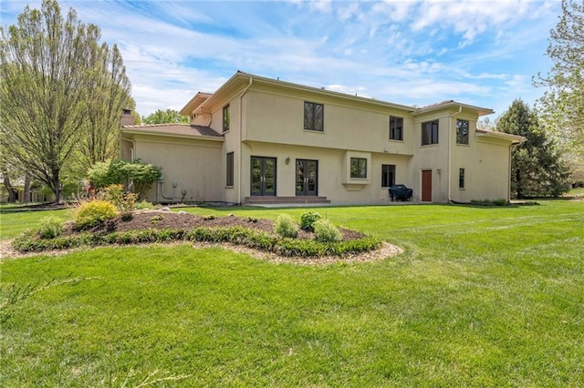 back of house featuring a yard, stucco siding, and french doors