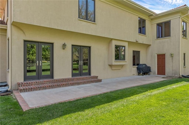 back of property featuring french doors, stucco siding, and a yard