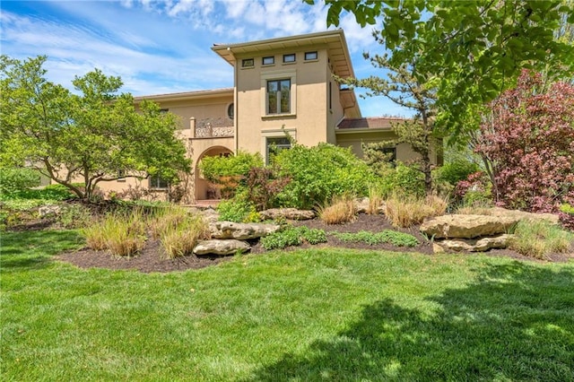 rear view of house with stucco siding and a lawn