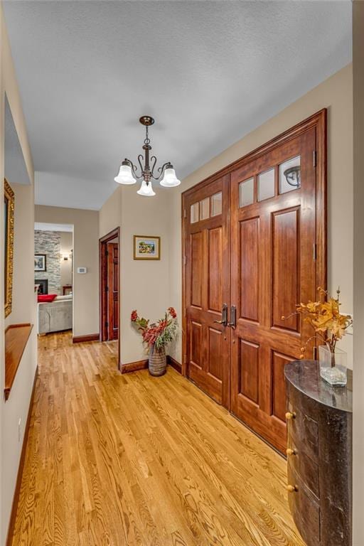entrance foyer featuring a chandelier, light wood-type flooring, and baseboards