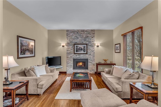 living room with wood finished floors and a stone fireplace