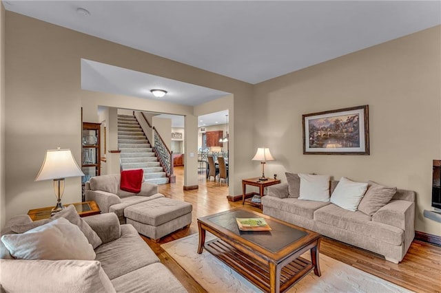 living room featuring stairs, light wood-style floors, and baseboards