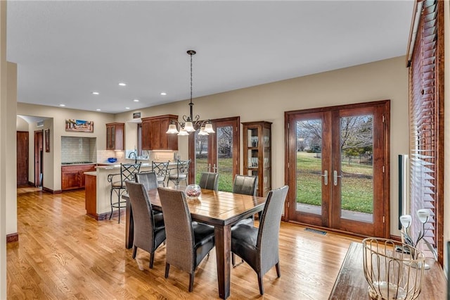 dining room featuring french doors, a chandelier, light wood-style flooring, recessed lighting, and baseboards
