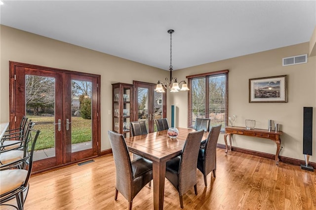 dining room featuring french doors, a chandelier, and light wood-style floors