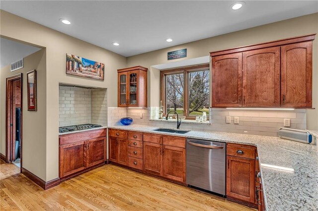 kitchen featuring appliances with stainless steel finishes, a sink, light wood-style flooring, light stone countertops, and recessed lighting