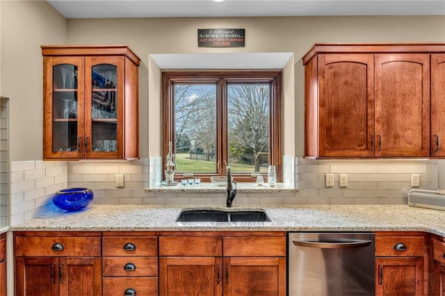 kitchen with stainless steel dishwasher, a sink, glass insert cabinets, light stone countertops, and backsplash