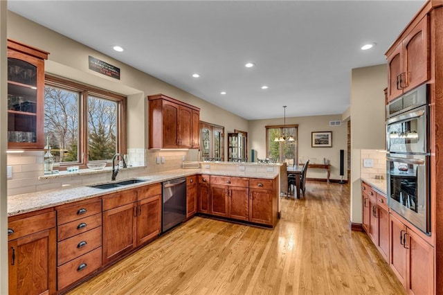 kitchen featuring appliances with stainless steel finishes, a peninsula, recessed lighting, a sink, and light wood finished floors