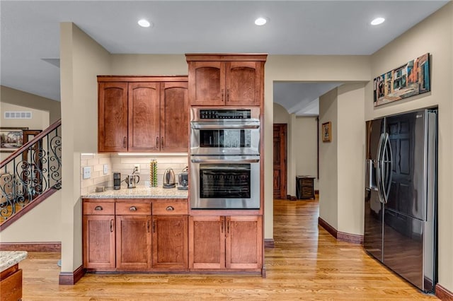 kitchen with fridge with ice dispenser, stainless steel double oven, light wood-style floors, backsplash, and recessed lighting