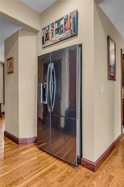 kitchen featuring refrigerator with ice dispenser, light wood-style floors, and baseboards