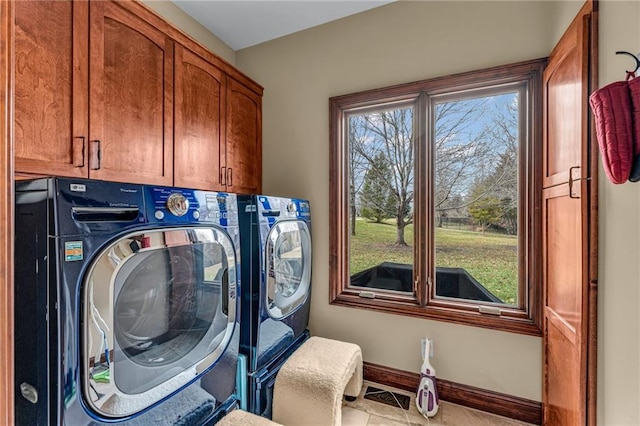 clothes washing area with cabinet space, washer and dryer, tile patterned floors, and baseboards