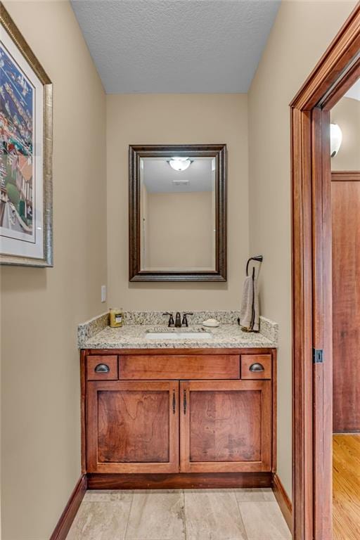 bathroom with vanity, baseboards, and a textured ceiling