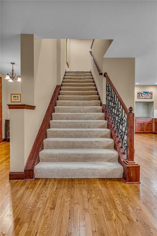 staircase with wood finished floors and a chandelier