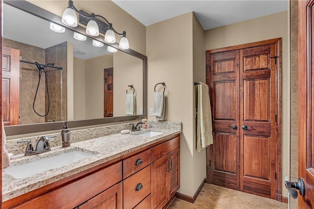 full bath with tiled shower, double vanity, tile patterned floors, and baseboards