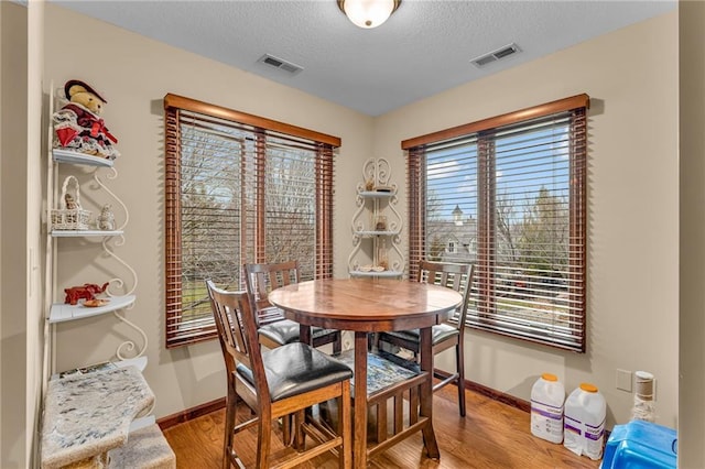 dining space with baseboards, wood finished floors, and a textured ceiling
