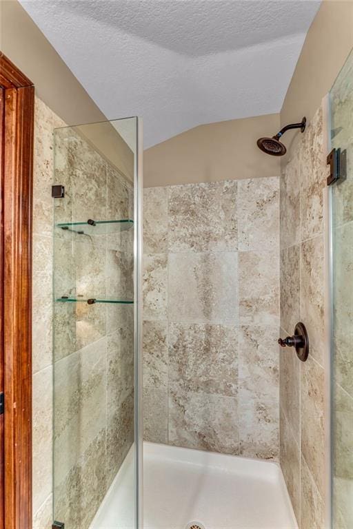 full bathroom with a shower stall, vaulted ceiling, and a textured ceiling