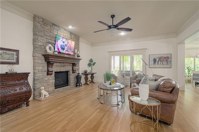 living room featuring a ceiling fan, ornamental molding, wood finished floors, and a fireplace