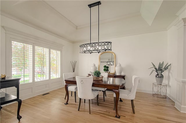 dining area featuring a raised ceiling, light wood-style flooring, crown molding, and a chandelier