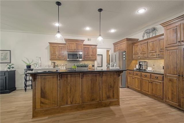 kitchen with appliances with stainless steel finishes, dark countertops, backsplash, light wood-style flooring, and pendant lighting