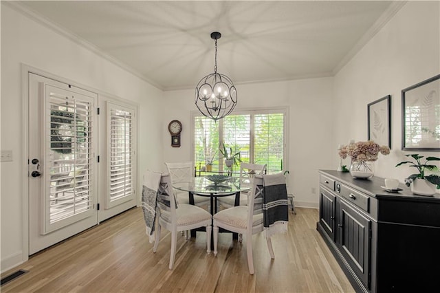 dining area with crown molding, a chandelier, and light wood finished floors