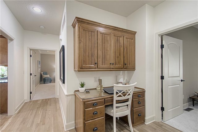 office featuring light wood-style flooring, built in study area, and baseboards