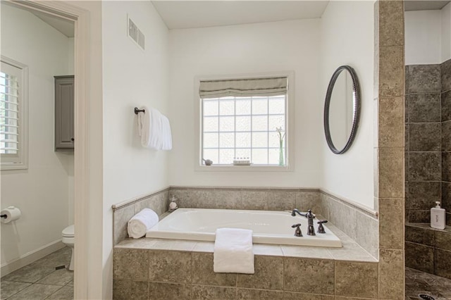 full bath featuring toilet, a garden tub, tile patterned flooring, and baseboards