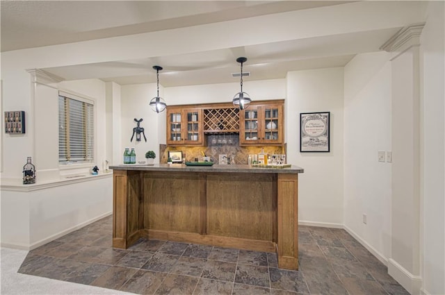 indoor wet bar featuring dark stone finish floors, tasteful backsplash, baseboards, and hanging light fixtures