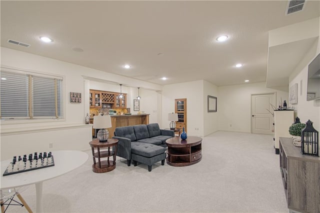 living room with light colored carpet, bar with sink, and recessed lighting