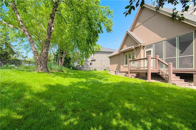view of yard featuring a sunroom and a wooden deck