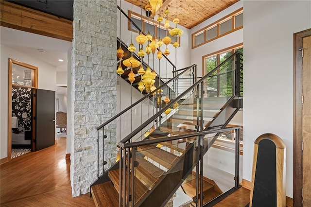 8700 Lee Blvd, Leawood, KS 66206 - stairway with wood finished floors, a chandelier, a towering ceiling, wood ceiling, and decorative columns
