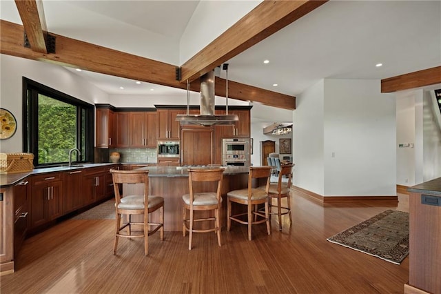 8700 Lee Blvd, Leawood, KS 66206 - kitchen featuring stainless steel appliances, beamed ceiling, wood finished floors, tasteful backsplash, and a kitchen bar