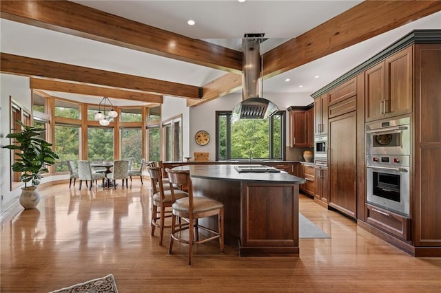 8700 Lee Blvd, Leawood, KS 66206 - kitchen with double oven, a center island, healthy amount of natural light, dark countertops, and beamed ceiling