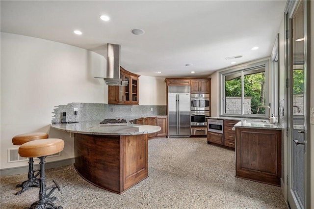 8700 Lee Blvd, Leawood, KS 66206 - kitchen with appliances with stainless steel finishes, wall chimney range hood, a peninsula, a sink, and decorative backsplash