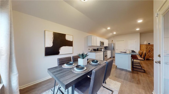 540 N Pecan St, Gardner, KS 66030 - dining area featuring wood finished floors, vaulted ceiling, recessed lighting, and baseboards