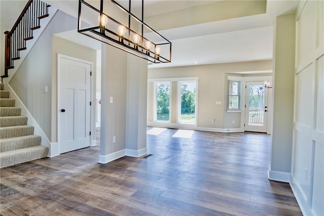 7812 N Spruce Ave, Kansas City, MO 64119 - unfurnished dining area featuring a chandelier, stairs, dark wood-type flooring, and baseboards