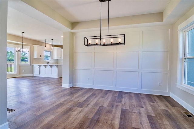 7812 N Spruce Ave, Kansas City, MO 64119 - unfurnished dining area featuring a chandelier, a decorative wall, dark wood-type flooring, plenty of natural light, and recessed lighting