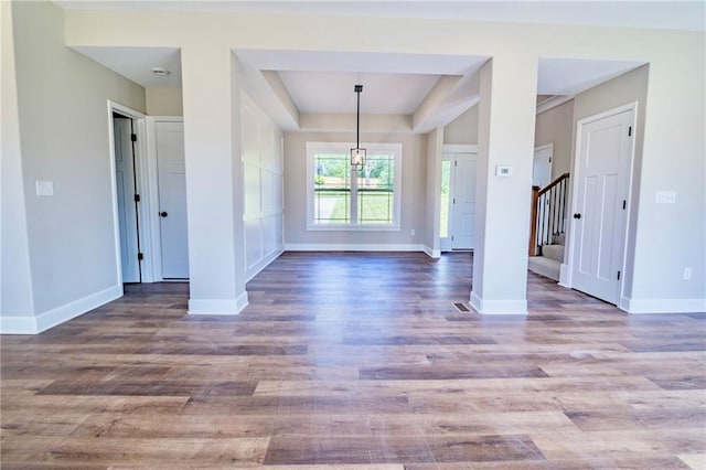 7812 N Spruce Ave, Kansas City, MO 64119 - unfurnished dining area featuring a tray ceiling, wood finished floors, stairs, and baseboards