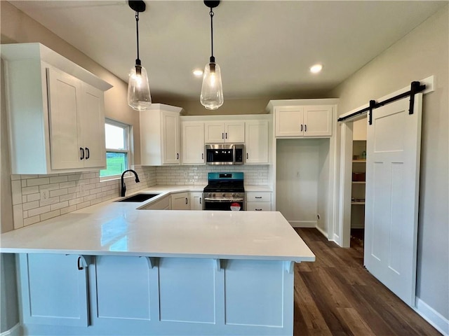 7812 N Spruce Ave, Kansas City, MO 64119 - kitchen featuring stainless steel appliances, a sink, a peninsula, white cabinets, and recessed lighting