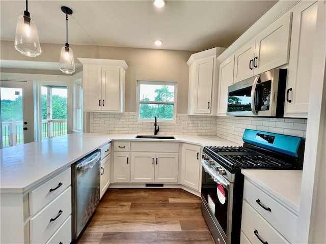 7812 N Spruce Ave, Kansas City, MO 64119 - kitchen featuring appliances with stainless steel finishes, a sink, a peninsula, white cabinetry, and dark wood-type flooring