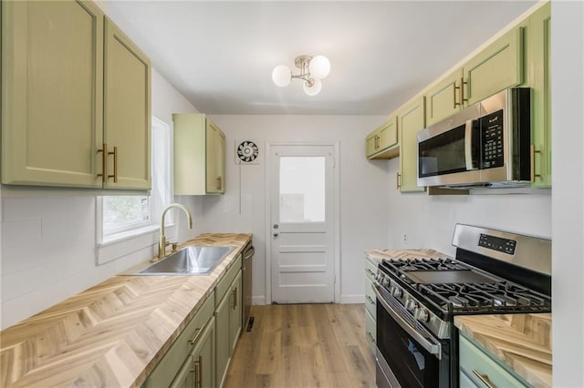 3113 55th St, Kansas City, MO 64119 - kitchen with appliances with stainless steel finishes, green cabinets, a sink, butcher block countertops, and light wood-style floors