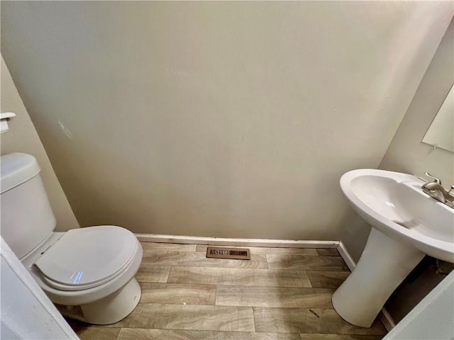 11914 E 59th Ter, Kansas City, MO 64133 - half bathroom with toilet, wood finished floors, and baseboards